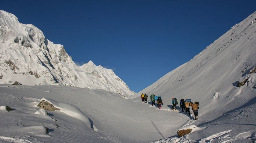 Adventure travellers trekking through mountain paths with panoramic landscapes and clear skies in Nepal